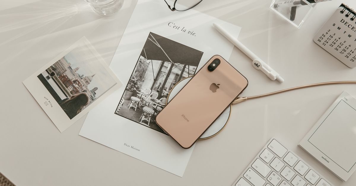 Aesthetic workspace featuring a smartphone, keyboard, and stationery in a warm, minimalist setup.